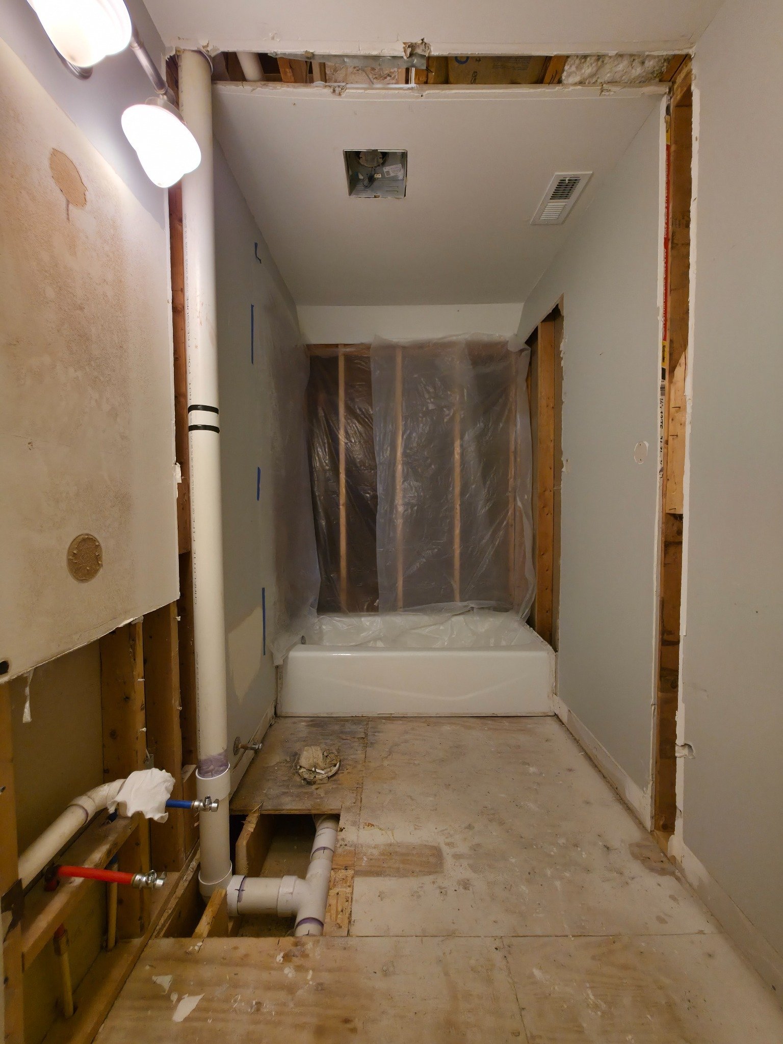 Bathroom demo showing full wall framing exposed, new tub in place, and subfloor open for plumbing in Carrboro NC