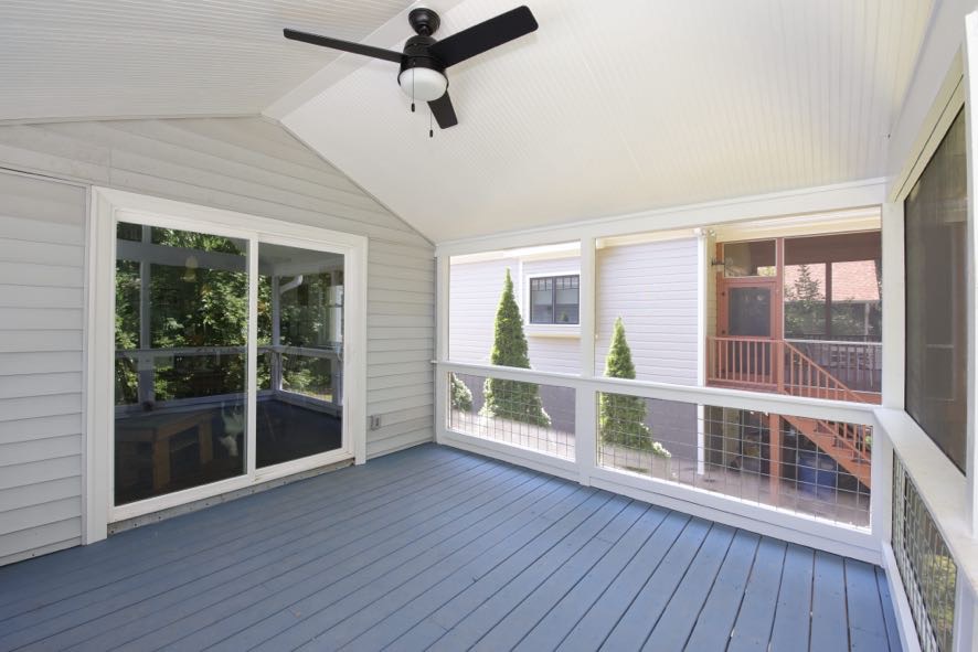 Screened porch interior with vaulted ceiling, ceiling fan, and sliding door to home in Durham NC