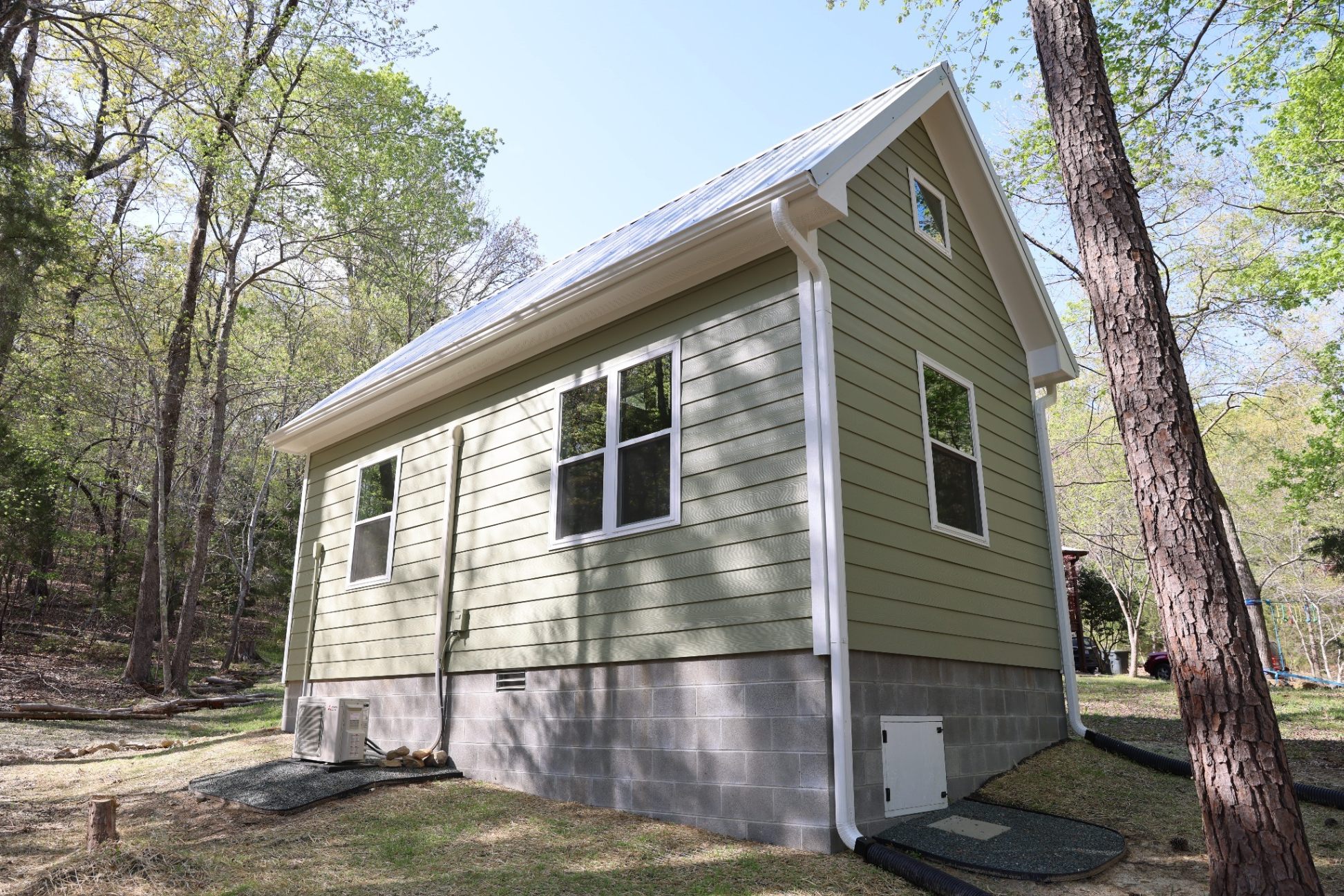 Side and rear exterior of completed office shed showing mini-split unit and CMU foundation in Durham NC