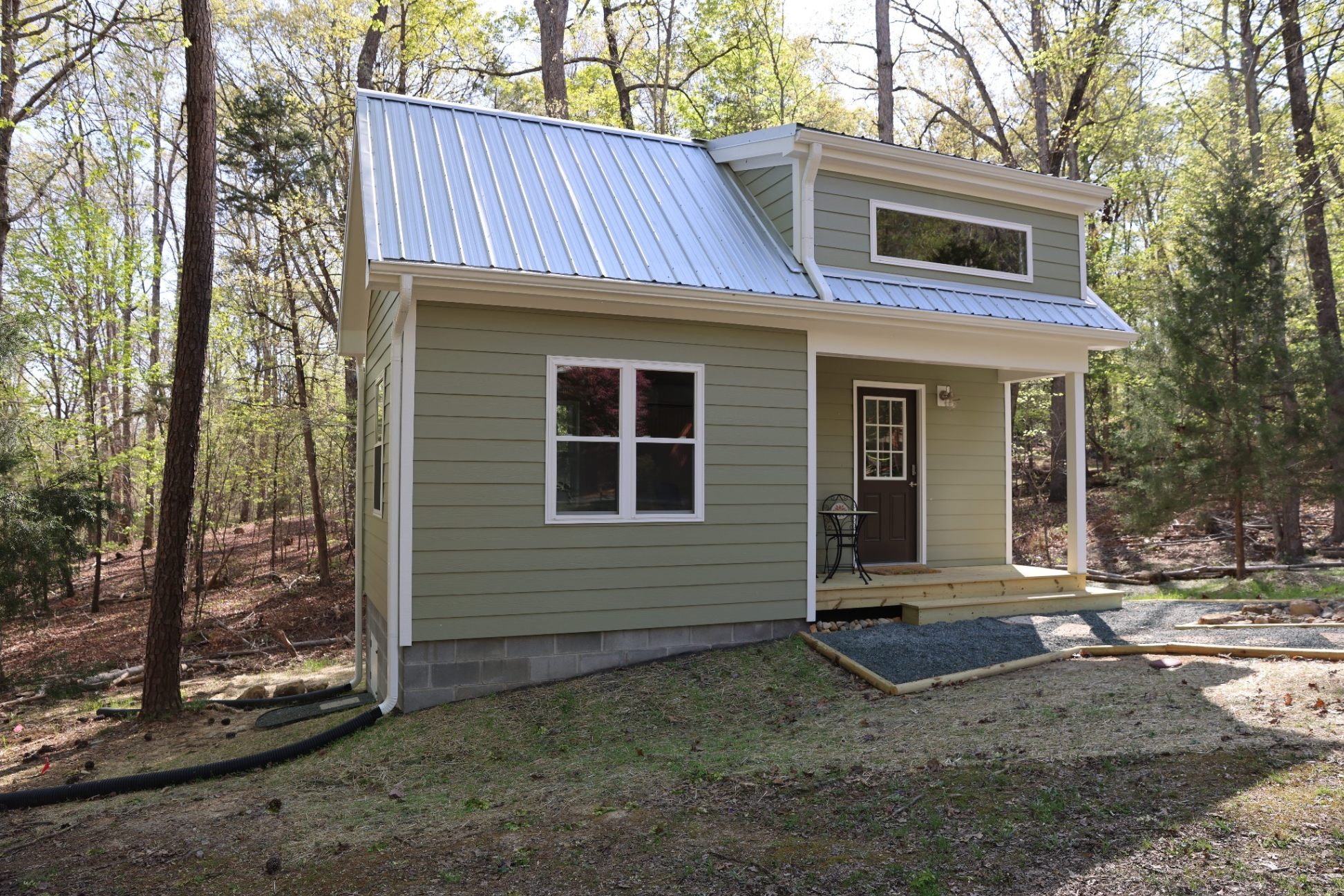 Completed backyard office shed exterior with covered entry porch and metal roof in Durham NC