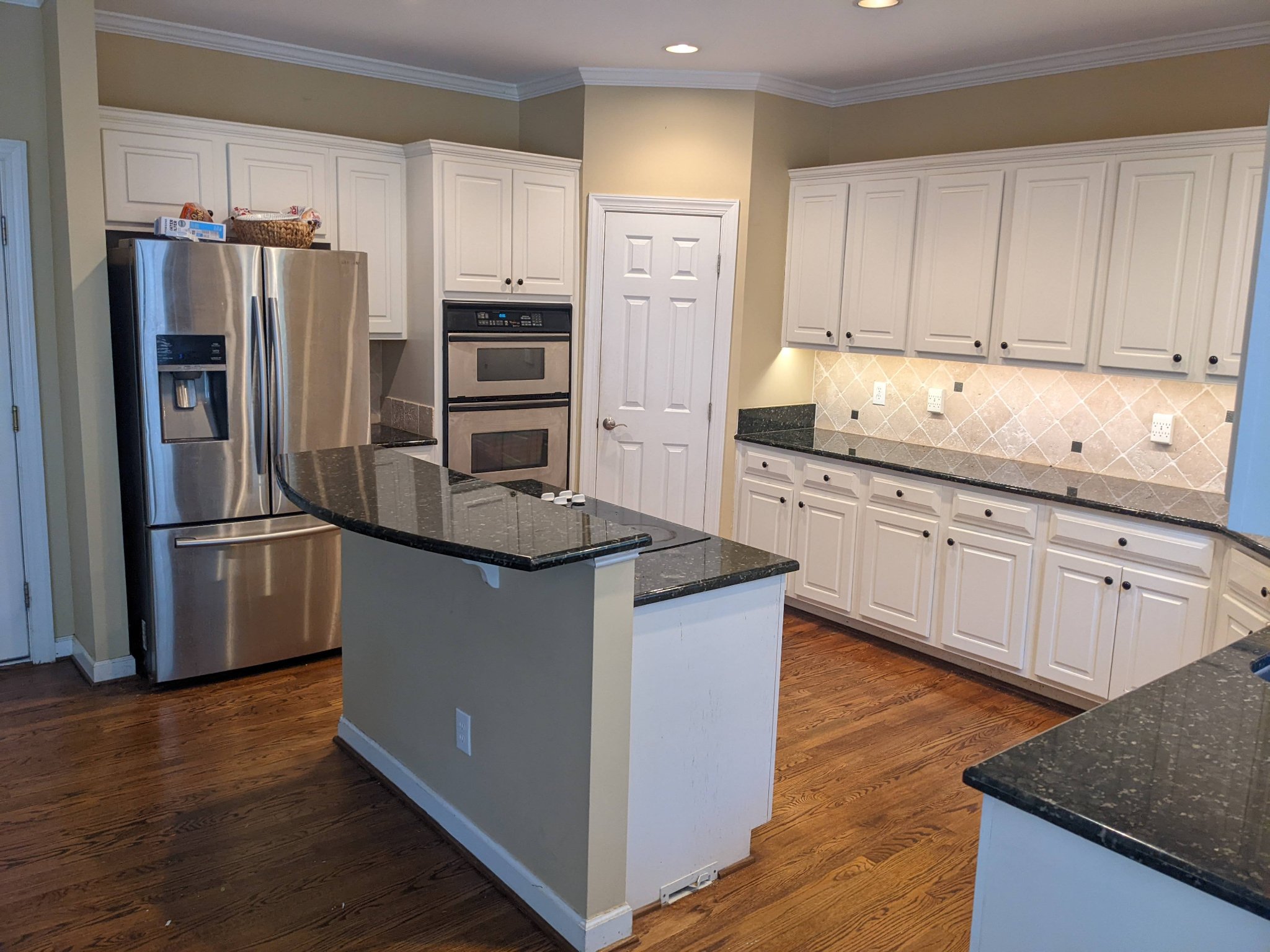 Original kitchen showing double wall oven, refrigerator, and diamond tile backsplash before remodel in Raleigh NC
