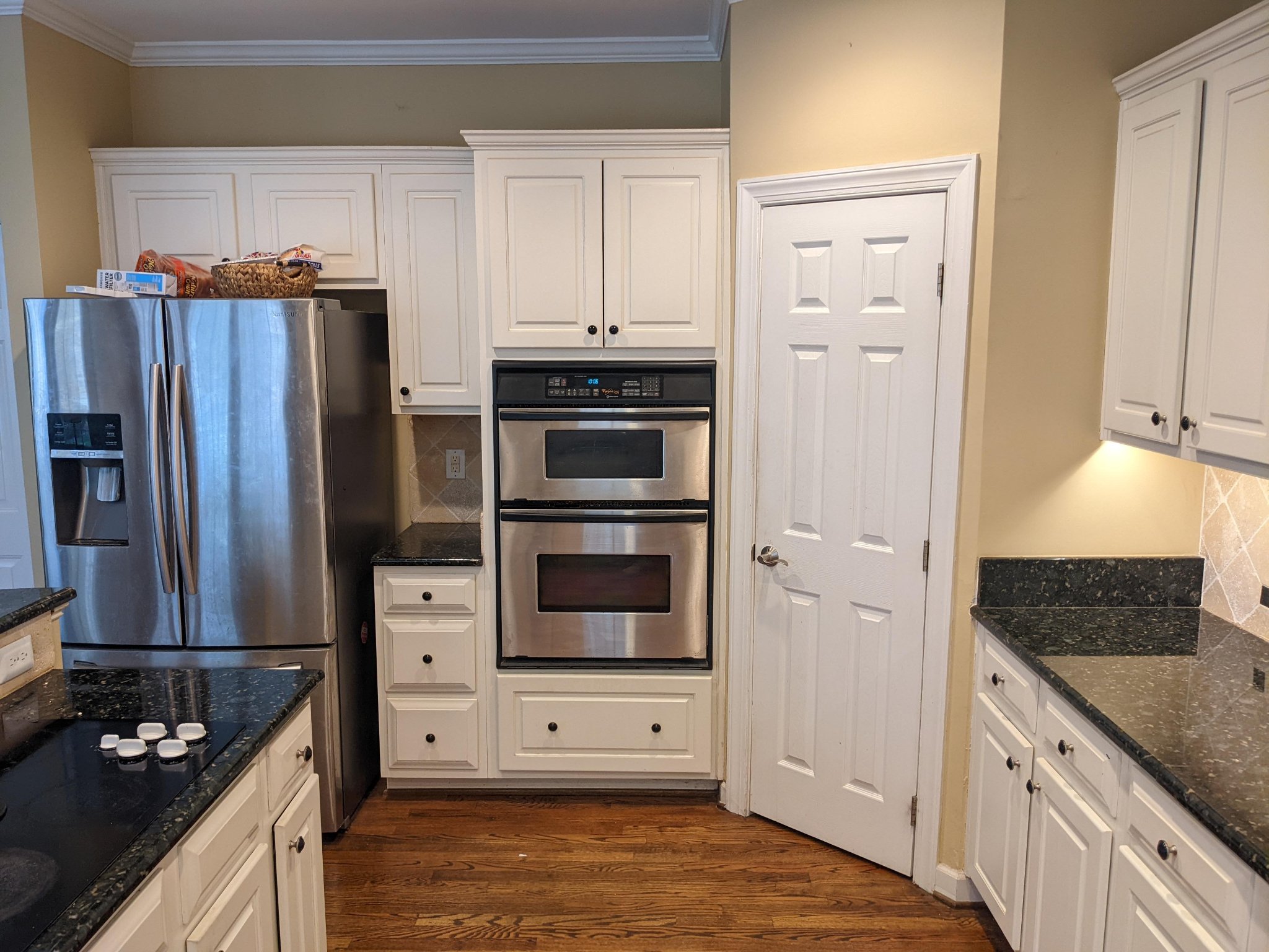 Original kitchen corner with double wall oven and dark granite counters before remodel in Raleigh NC