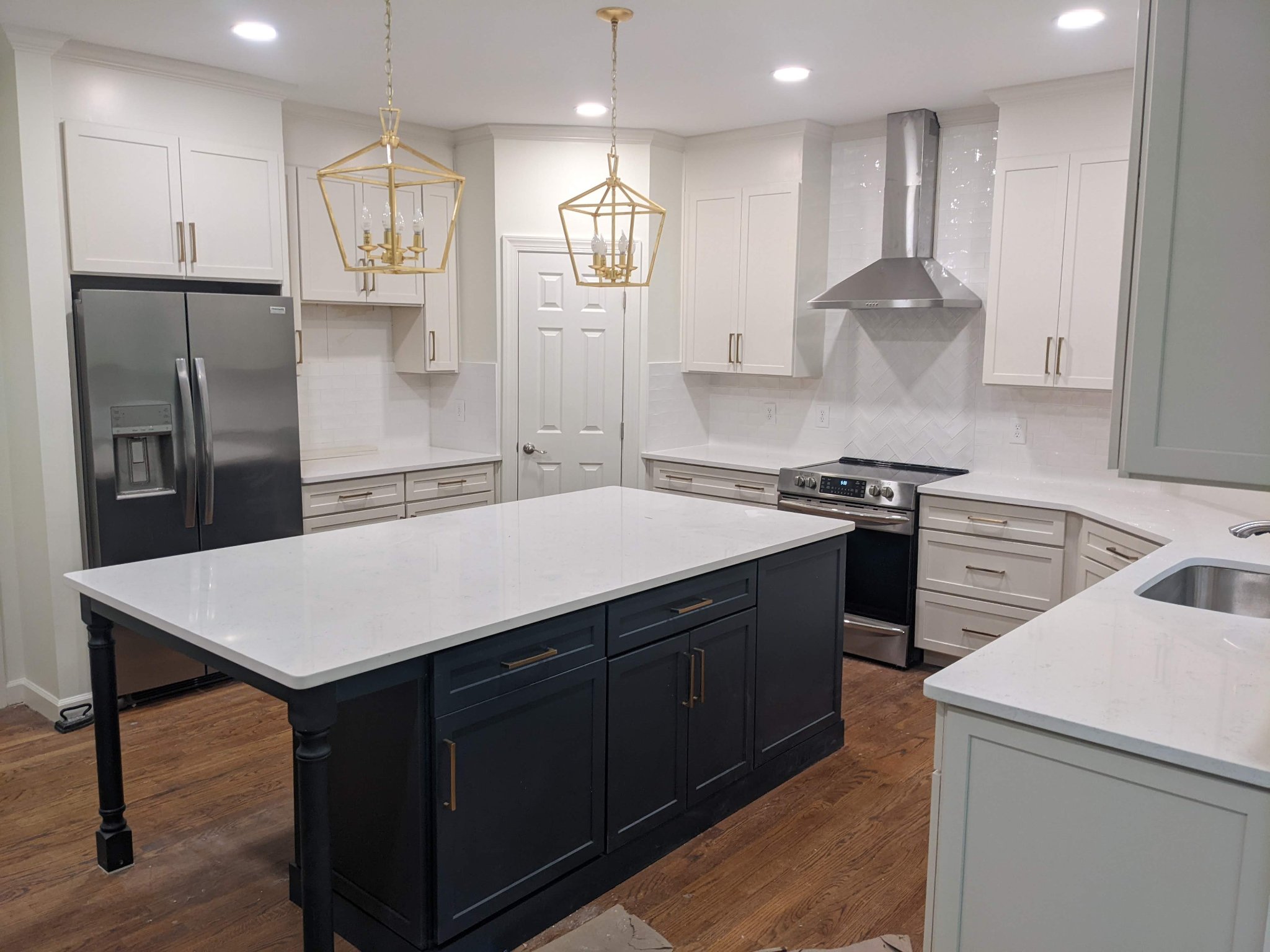 Completed kitchen remodel with two-tone shaker cabinets, quartz counters, and gold lantern pendants in Raleigh NC