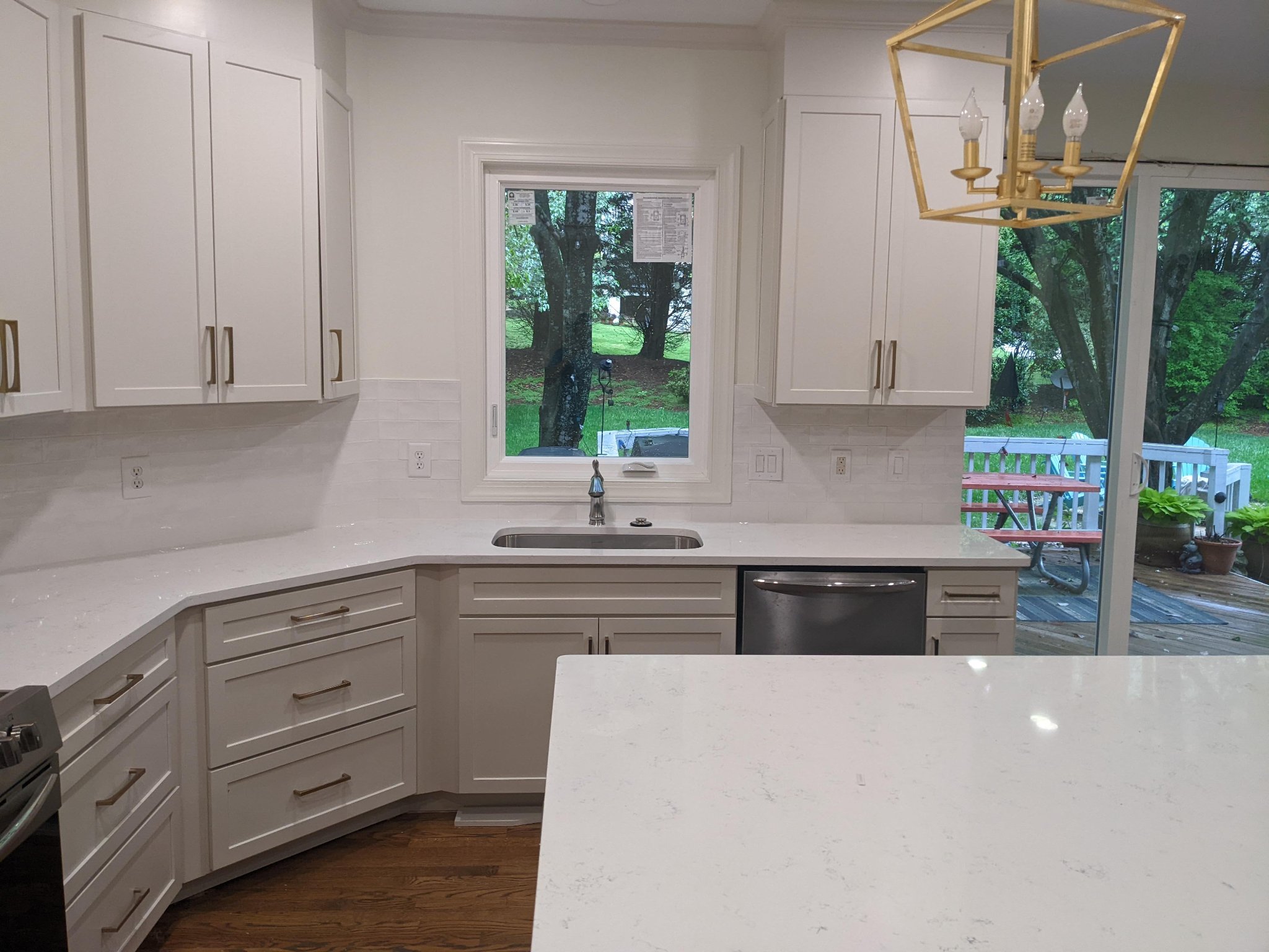 Completed kitchen sink wall with white shaker cabinets, quartz counters, and subway tile backsplash in Raleigh NC