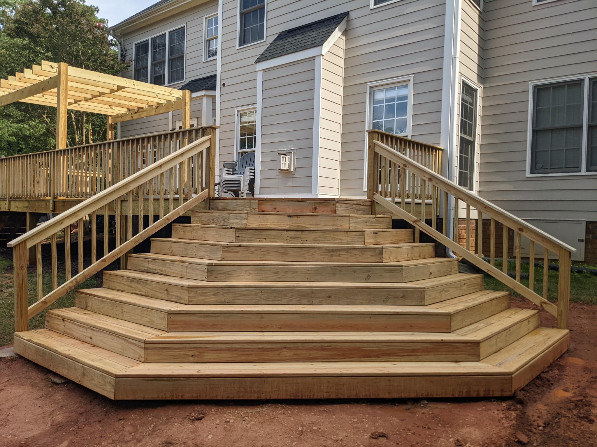 Wide wraparound stair system on completed elevated deck with pergola in Raleigh NC