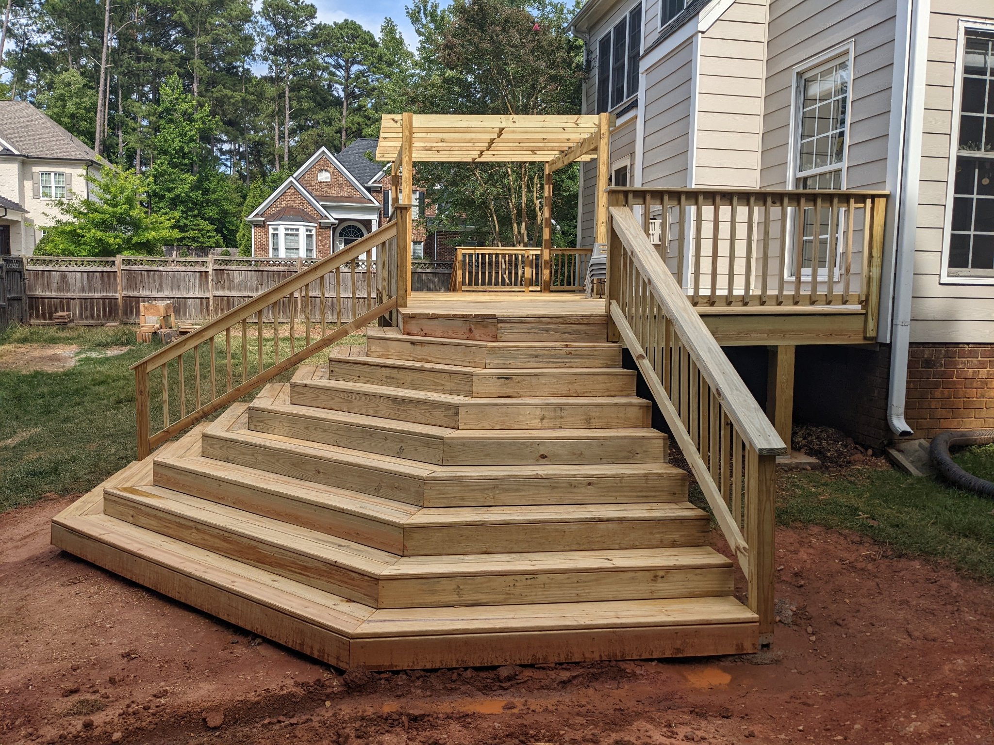 Angled view of completed deck stair system with pergola and railing in Raleigh NC