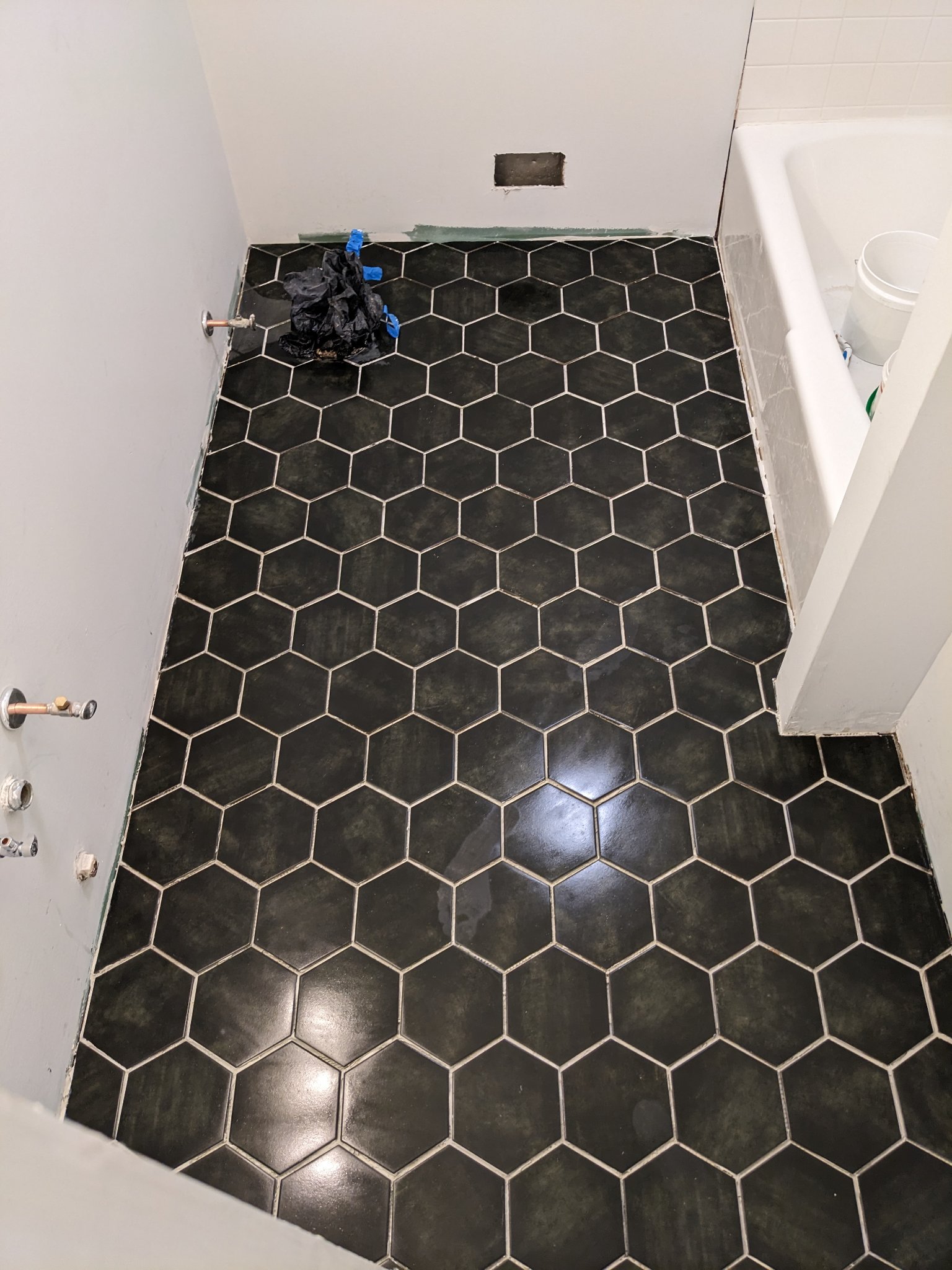 Large format black hex tile fully set and grouted on bathroom floor in Raleigh townhouse