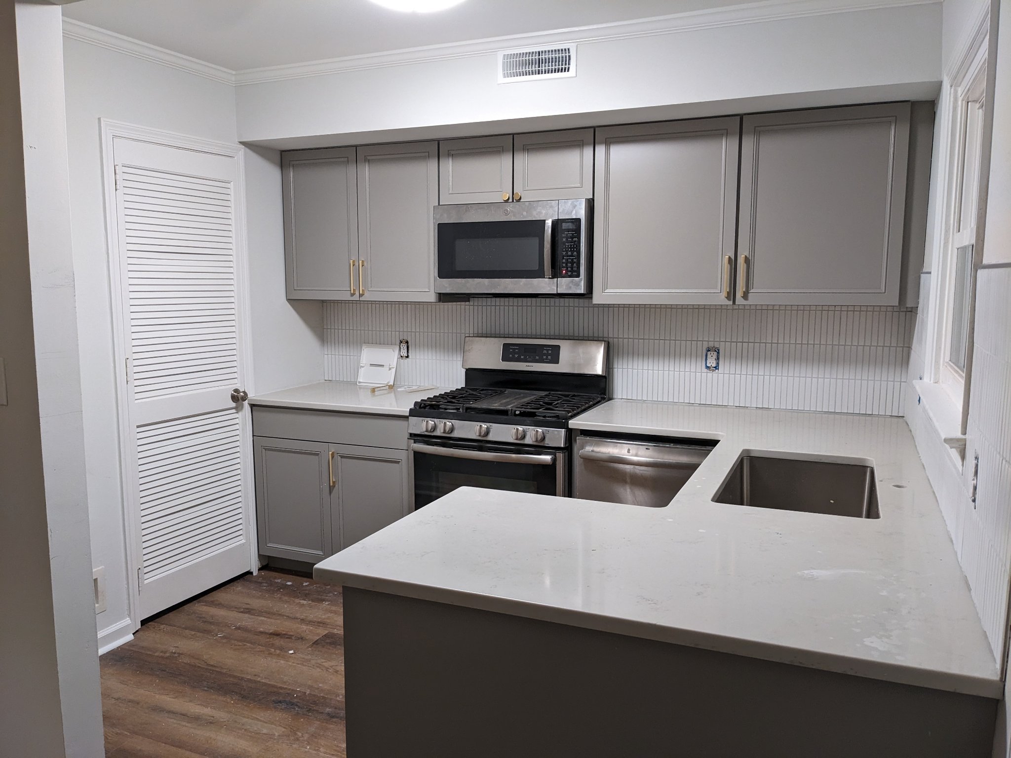 Finished kitchen with gray shaker cabinets, quartz countertops, subway tile backsplash, and hardwood floors in Raleigh townhouse
