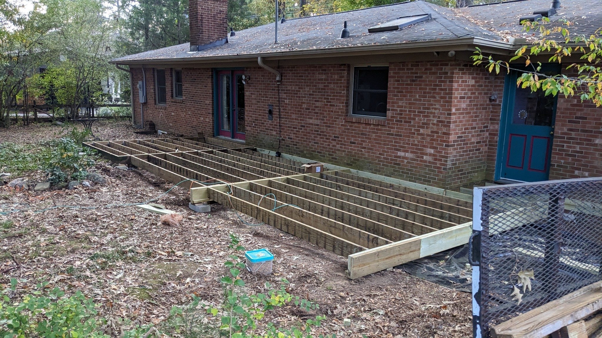 New pressure-treated deck framing installed on existing footings during screened porch construction in Carrboro NC