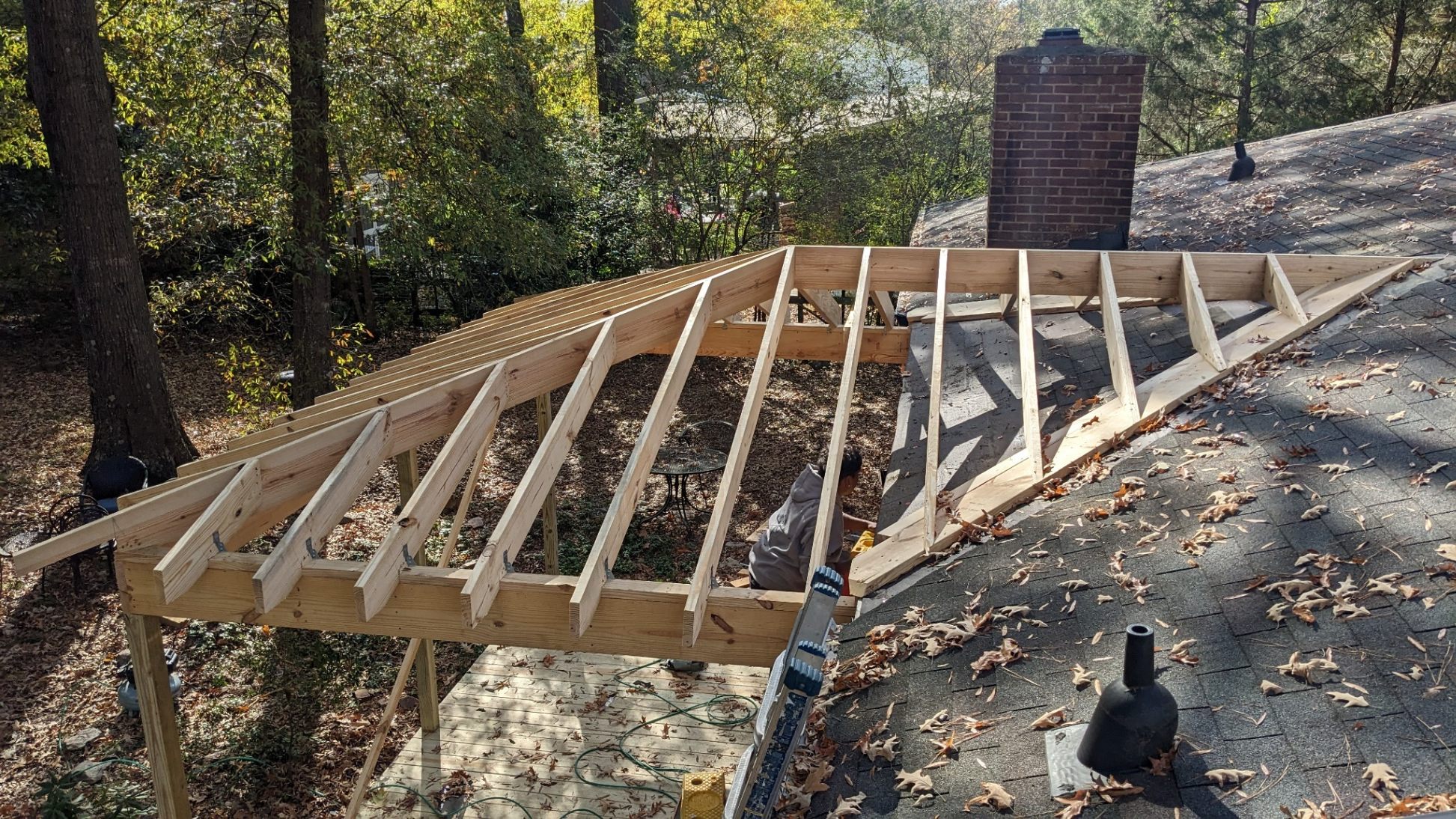 Hip roof rafters framed over new deck platform viewed from above during screened porch construction in Carrboro NC