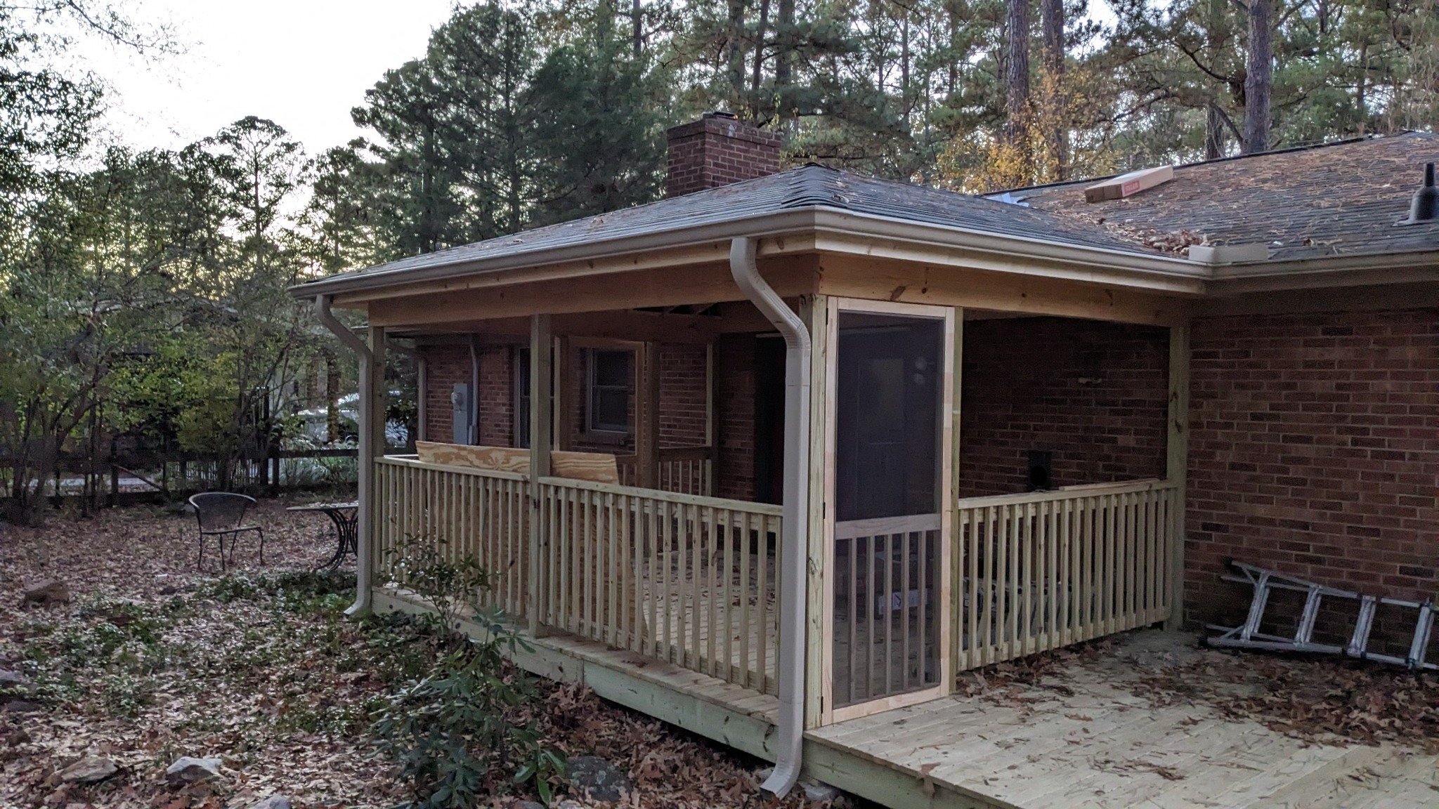 Painting crew applying white paint to screened porch railing, columns, and trim during finishing in Carrboro NC